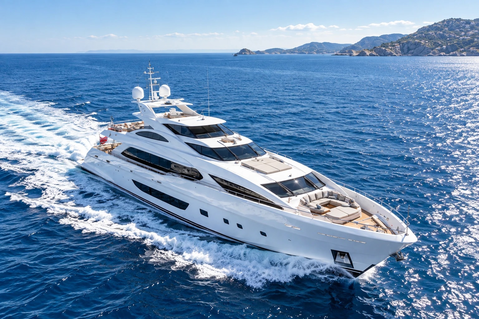 A white superyacht cruising across the sparkling blue Mediterranean Sea